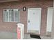 A ground-level exterior shot of a brick building, showcasing a white door and window with curtains at 241 Presidential Dr., Surfside Beach, SC 29575