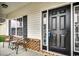 Front porch with black door and small sitting area at 4060 Woodcliffe Dr., Conway, SC 29526