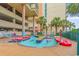 Outdoor lazy river with palm trees, lounge chairs, and adjacent parking located at the building of a resort complex at 501 S Ocean Blvd. # 708, North Myrtle Beach, SC 29582
