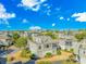 Expansive aerial view of a neighborhood showcasing uniform, stylish homes with rooftop decks under a bright blue, cloudy sky at 1609 Harbor Dr., North Myrtle Beach, SC 29582