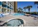 Resort-style pool and hot tub area surrounded by brick patio, lounge chairs, and palm trees for leisure at 2504 N Ocean Blvd. # 832, Myrtle Beach, SC 29577