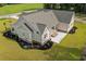 A high angle view of a backyard featuring a covered patio, green grass, mature trees, and landscaping at 3220 Highway 19, Conway, SC 29526