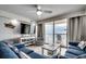 Relaxing living room featuring comfortable seating, large TV, ocean view, and balcony access at 1012 N Waccamaw Dr. # 902, Murrells Inlet, SC 29576