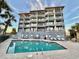 Building exterior with inviting pool area and palm trees at 1906 S Ocean Blvd. # 108A, Myrtle Beach, SC 29577