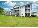 White building with balconies and lush green lawn at 557 White River Dr. # 12A, Myrtle Beach, SC 29579