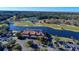 Aerial view of a golf course with a clubhouse, surrounded by lush greenery, a serene lake, and abundant trees at 1245 Lady Bird Way, North Myrtle Beach, SC 29582