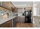 Basement kitchenette with dark wood cabinets, granite counters, and black appliances at 304 Spartina Ct., North Myrtle Beach, SC 29582