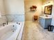 Bright bathroom features a soaking tub, marble floors, and a blue vanity with marble countertop at 926 Eula Dr., Conway, SC 29526