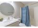 Bright bathroom featuring a white vanity with a round mirror, toilet and a shower with a blue curtain at 1100 Possum Trot Rd. # H234, North Myrtle Beach, SC 29582