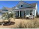 Charming, light blue home with a covered porch and a well-manicured front yard with a small palm tree at 1310 Beautyberry Way, North Myrtle Beach, SC 29582