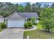 Charming single-story home with a well-manicured lawn, gray siding and attached two-car garage and driveway at 184 Retreat Pl., Little River, SC 29566