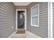 Cozy, covered front porch featuring neutral siding, decorative window, door wreath and welcoming 'hi' doormat at 184 Retreat Pl., Little River, SC 29566