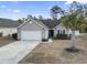 House exterior with gray siding, two-car garage, and landscaping at 293 Foxpath Loop, Myrtle Beach, SC 29588