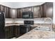 Modern kitchen with dark brown cabinets, black appliances, and speckled countertops at 293 Foxpath Loop, Myrtle Beach, SC 29588