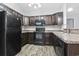 L-shaped kitchen with dark brown cabinets and black appliances at 293 Foxpath Loop, Myrtle Beach, SC 29588