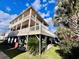 Three-story beach house with wrap-around deck and palm trees at 6001 - 6004 S Kings Hwy., Myrtle Beach, SC 29575