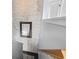 Hallway with a painted brick wall, wood railing, decorative mirror and a glimpse into a well-lit living space at 817 Old Castle Loop, Myrtle Beach, SC 29579