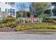 A welcoming community entrance sign surrounded by colorful seasonal flowerbed, mature shrubbery, and a waving American flag at 901 West Port Dr. # 1706, North Myrtle Beach, SC 29582