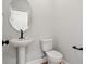 A modern half bathroom featuring a sleek pedestal sink, round mirror, black fixtures, and white toilet at 1201 Possum Trot Rd., North Myrtle Beach, SC 29582