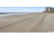Wide sandy beach with tire tracks leading to ocean at 1205 S Ocean Blvd. # 50412, Myrtle Beach, SC 29577