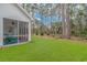 Screened porch with Adirondack chairs overlooks a spacious backyard at 121 Crossroad Dr. Nw, Calabash, SC 28467