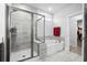 Elegant bathroom featuring gray tiled walls, a walk-in shower, soaking tub, and bright natural light at 1410 Saw Palmetto St., North Myrtle Beach, SC 29582
