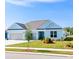 Charming light blue home featuring a manicured lawn, colorful flower beds, and a two-car garage at 1410 Saw Palmetto St., North Myrtle Beach, SC 29582