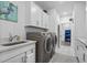 Bright laundry room featuring white cabinetry, gray washer/dryer, sink, and an open doorway at 1410 Saw Palmetto St., North Myrtle Beach, SC 29582