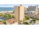 A full exterior view shows the high-rise building near the beach with a parking area, trees, and blue sky at 210 75Th Ave N # 4010, Myrtle Beach, SC 29572