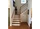 Inviting staircase with wooden steps, white railings, and a colorful stained-glass window at the landing at 41 Federation Loop, Pawleys Island, SC 29585
