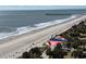 Scenic beach view with colorful sunshades, palm trees, and distant pier under a sunny sky at 504 N Ocean Blvd. # 1003, Myrtle Beach, SC 29577