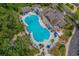 Aerial view of a large community pool featuring sun loungers, umbrellas, and a spacious clubhouse area at 7053 Byrnes Ln., Myrtle Beach, SC 29588