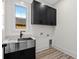 Well-equipped laundry room with black cabinets, stainless steel sink, and stylish faucet for added convenience at 7053 Byrnes Ln., Myrtle Beach, SC 29588