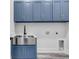 Modern laundry room with blue cabinets, stylish sink, gold hardware, and sleek design for efficient functionality at 7053 Byrnes Ln., Myrtle Beach, SC 29588