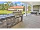 Covered outdoor kitchen with built-in grill, stone counter, and a view of the landscaped backyard at 7053 Byrnes Ln., Myrtle Beach, SC 29588