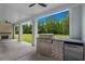 Outdoor kitchen features a built-in grill and bar on a covered patio with ceiling fans at 7053 Byrnes Ln., Myrtle Beach, SC 29588