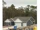 New construction home featuring three-car garage, blue siding, and a well-manicured yard at 25 Northbrook Dr, Murrells Inlet, SC 29576