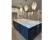 Kitchen island featuring navy cabinetry, white countertops, geometric pendants and hardwood floors throughout at 25 Northbrook Dr, Murrells Inlet, SC 29576