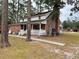 Back exterior of a home with brick siding, white trim, covered porch and lots of trees at 305 W Raft St., Nichols, SC 29581