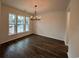 Open dining room with three windows, hardwood floors, and a stylish chandelier at 35 Northbrook Dr, Murrells Inlet, SC 29576