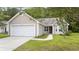 Tan house with a white garage door and a well-maintained lawn at 363 Junco Circle, Longs, SC 29568