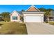 Suburban home with two-car garage, well-manicured lawn, and neutral color scheme at 409 Carrick Loop, Longs, SC 29568