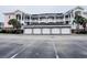 Three-story condo building featuring brick-based garages and pink siding at 4846 Carnation Circle # 203, Myrtle Beach, SC 29577