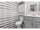 Small bathroom with a toilet, cabinet, mirror, sink, and striped shower curtain, providing a functional layout at 901 Queensferry Ct., Conway, SC 29526