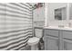 Bathroom with gray vanity, striped shower curtain, and linen cabinet at 901 Queensferry Ct., Conway, SC 29526