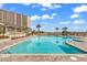 Outdoor community pool with lounge chairs, tropical landscaping, and palm trees at 415 Ocean Creek Dr. # 2139, Myrtle Beach, SC 29572