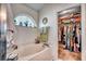 Bathroom with a soaking tub, window, and walk-in closet filled with clothing at 1579 Southwood Dr., Surfside Beach, SC 29575