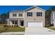 Two-story house with beige siding, white garage door, and landscaping at 511 Firouz Dr, Longs, SC 29568
