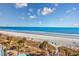 Wide beach view with picnic tables on land and views of sunlit ocean waters perfect for vacationing at 201 74Th Ave. N # 2640, Myrtle Beach, SC 29572