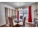 Bright dining room with glass table and four chairs, plus neutral colored curtains at 575 Mossbank Loop, Longs, SC 29568